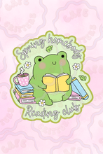 Load image into Gallery viewer, Sticker with a green frog reading a yellow book, surrounded by stacked books, a pink polka dot mug, white daisies, and leafy accents. The text reads “Spring Homebody Reading Club,” giving the design a cozy Cafe Critterz book club feel for springtime readers.
